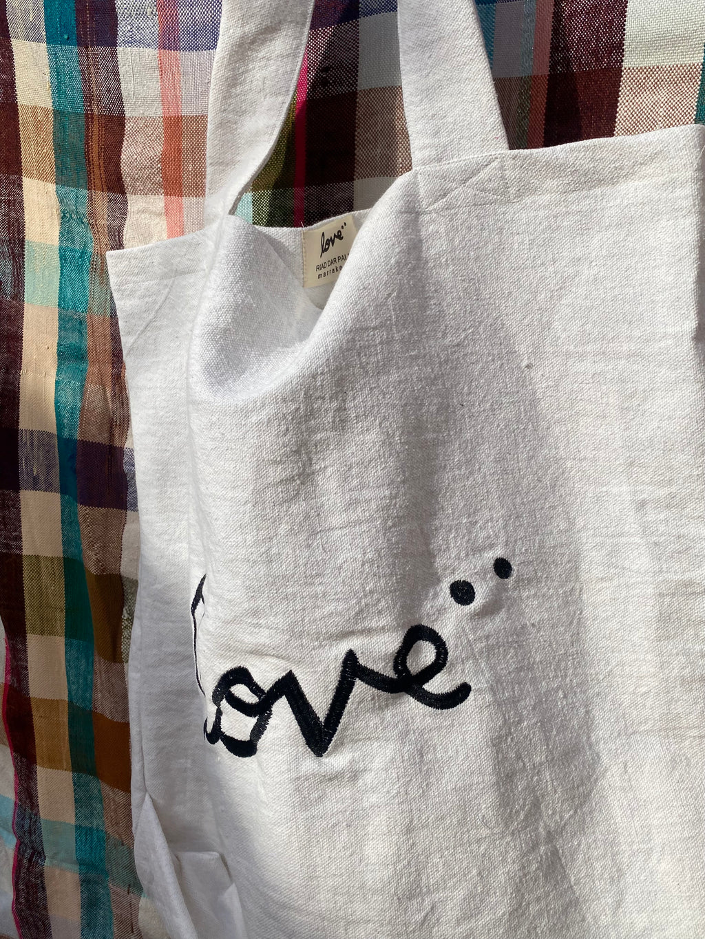 Close-up of hand-embroidered love script on white tote bag — Made in Morocco