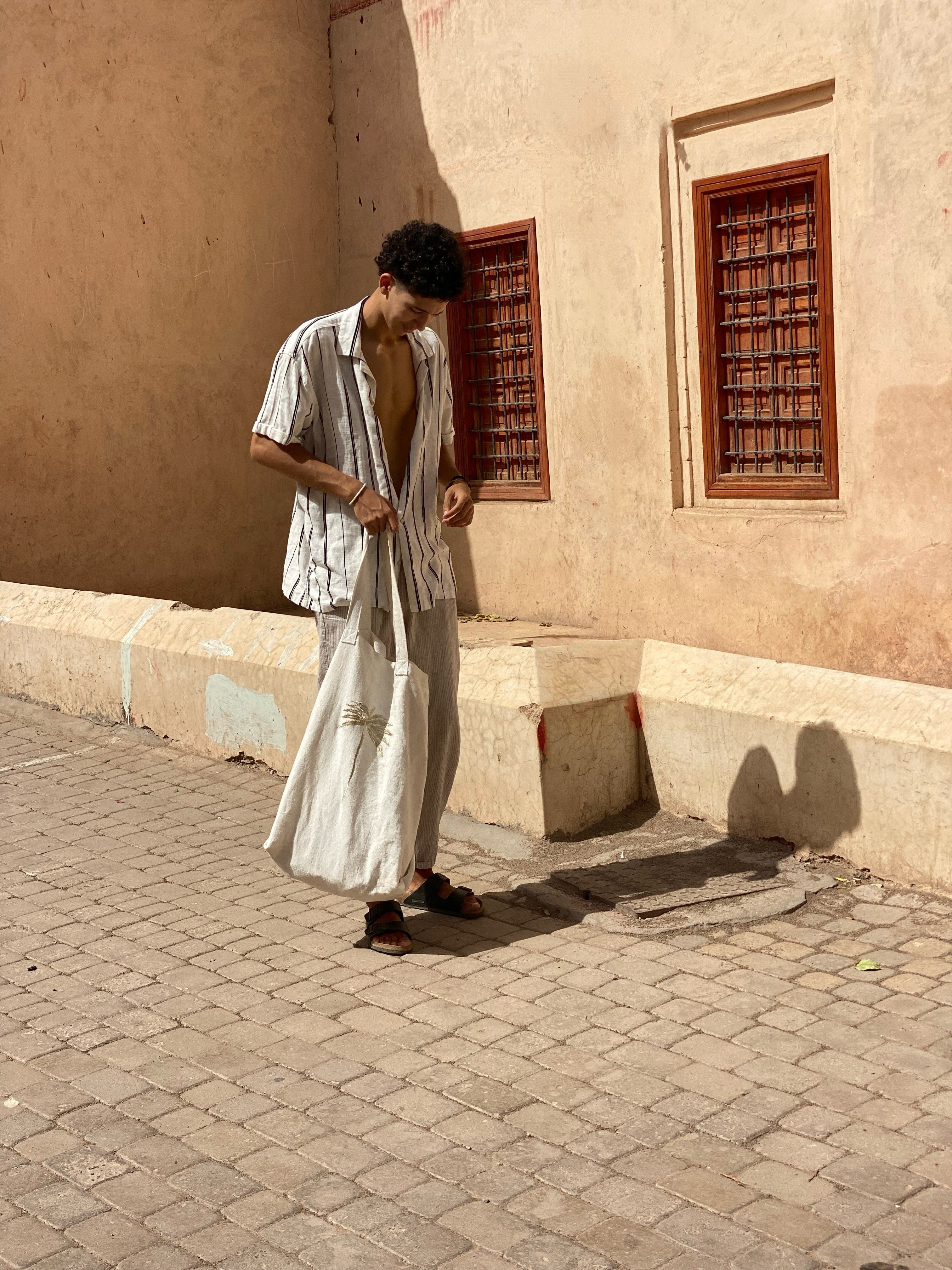 Man carrying handmade white linen tote bag in Moroccan medina — Souhaib Creative Service