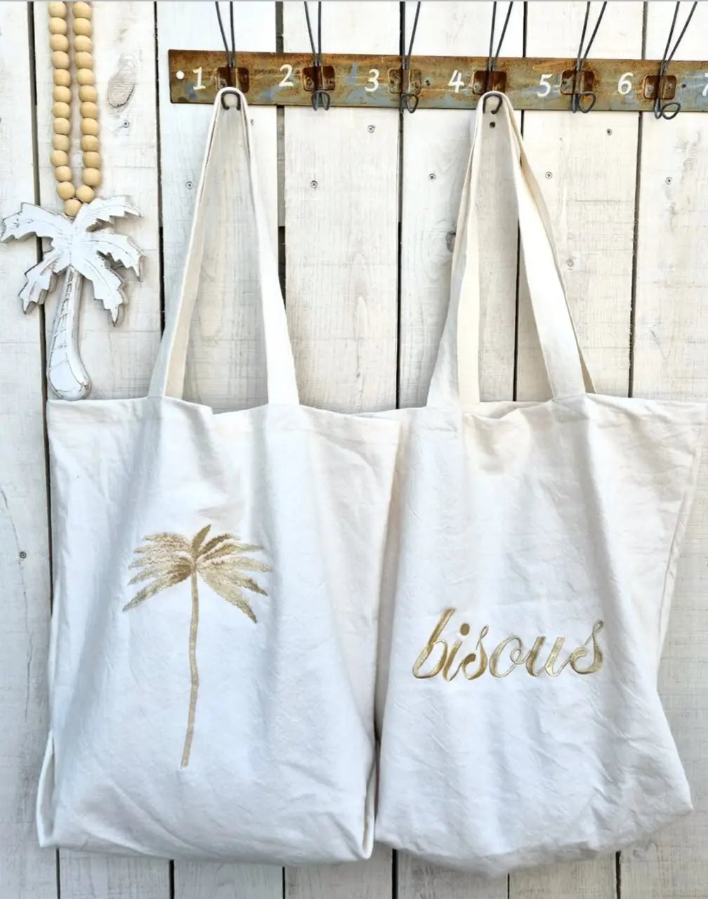Canvas tote bags with gold embroidered palm tree and bisous script for beach and everyday use.